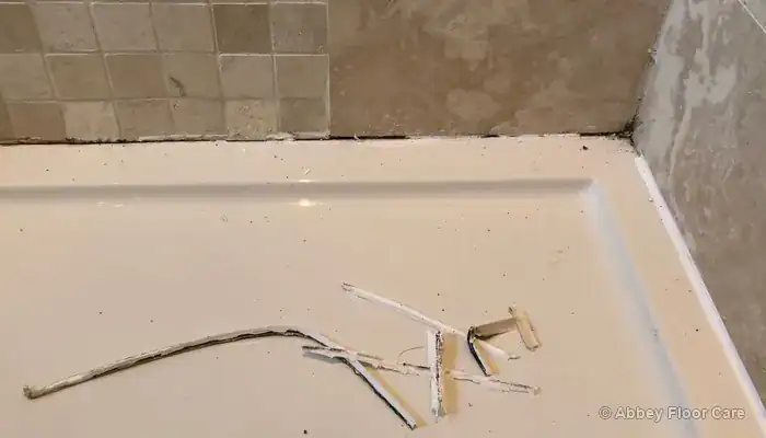 Travertine shower floor with blackened grout around the stone tiles