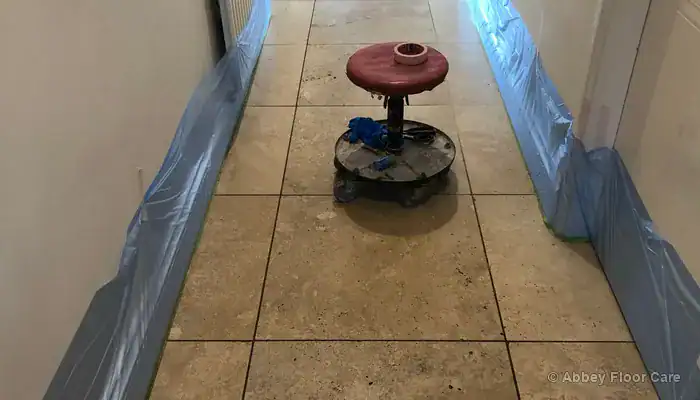 Travertine hallway floor with black grout lines through the main walking area