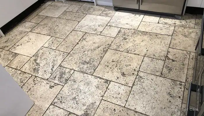 Travertine floor with heavily discoloured grout contrasting against the surrounding stone tiles
