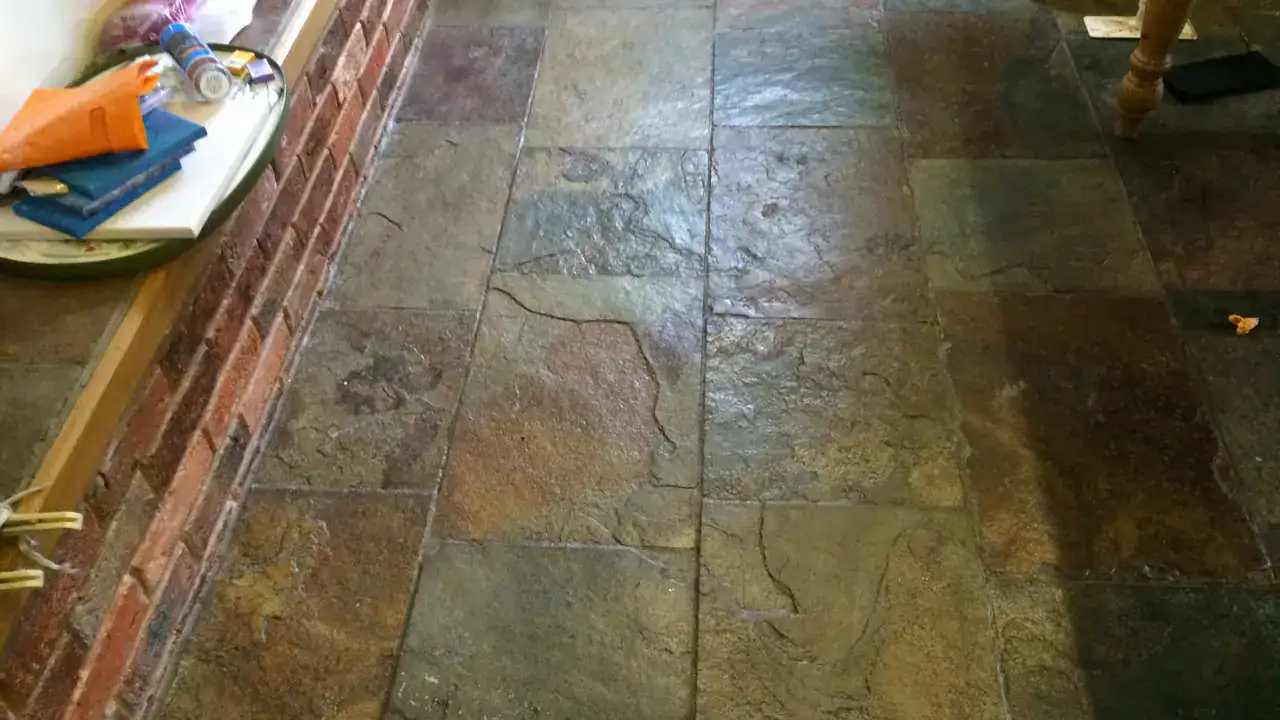 Patchy slate floor with heavy wax build-up and surface breakdown
