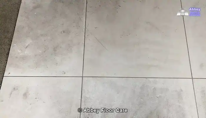 Limestone floor showing dull patches, fine scratches, and cloudy etch marks under angled lighting