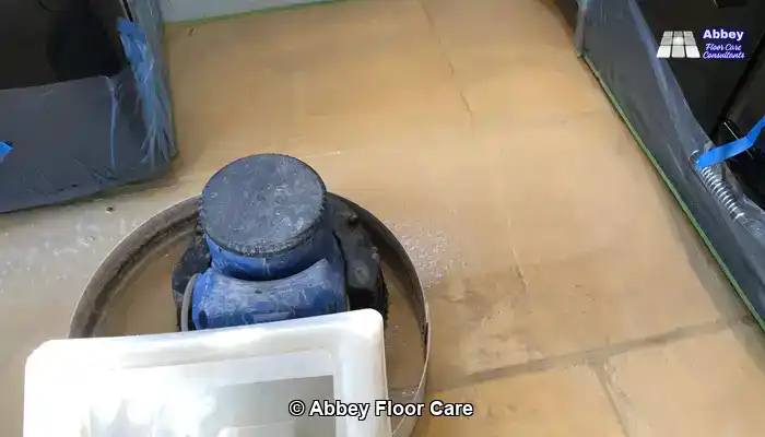 Technician using pH-neutral stone cleaner on limestone tiles using rotary floor machine