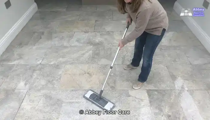 Restored tumbled travertine floor being gently mopped with a pH-neutral stone cleaner