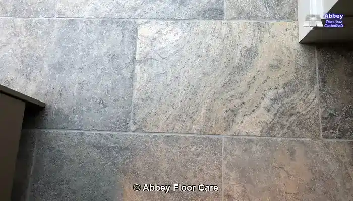 Travertine floor being inspected with cracks and pits highlighted and nearby areas carefully masked