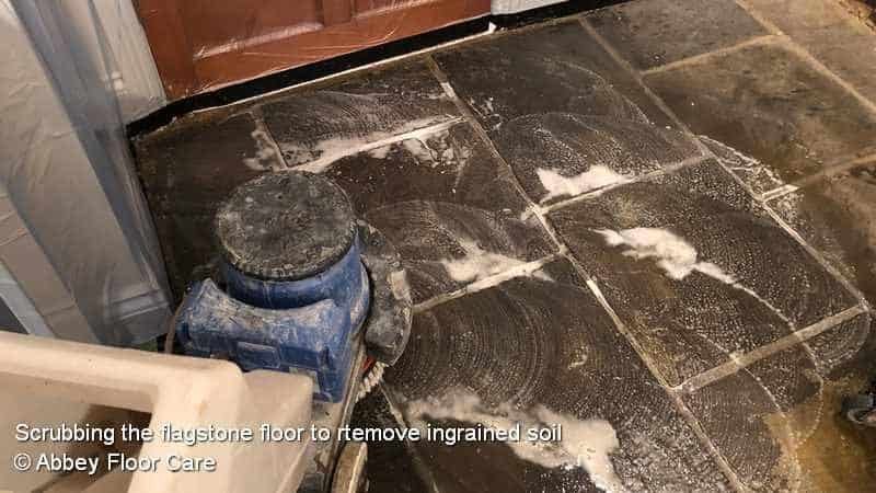 scrubbing a flagstone floor to remove ingrained dirt