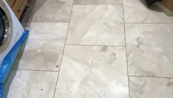 Etch marks and dull patches on a marble floor caused by acidic contact