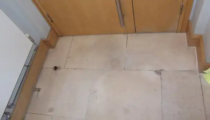 Small chip in a limestone floor surface that disrupts an otherwise even finish