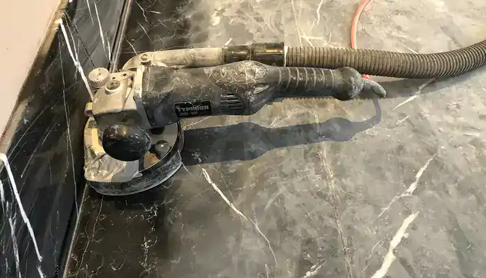 Detail honing along the edge of a marble floor using hand diamond tools