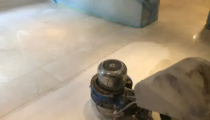Technician honing a marble floor using diamond abrasives and controlled slurry management