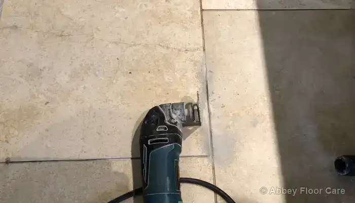 Cracked travertine tile with surrounding grout removed to expose the edges of the stone.