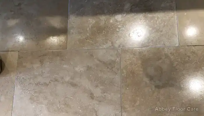 Replacement travertine tiles fitted flush with the surrounding floor surface.