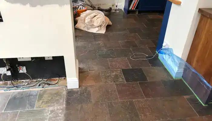 Slate tiles showing uneven colour where walkways have worn more than surrounding areas.