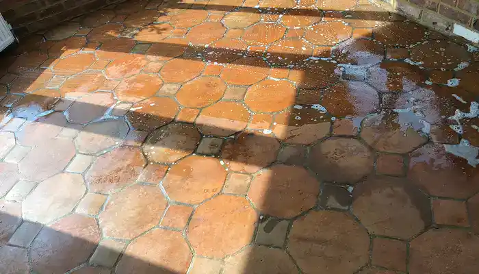 Terracotta floor tiles drying after cleaning, with darker patches showing retained moisture
