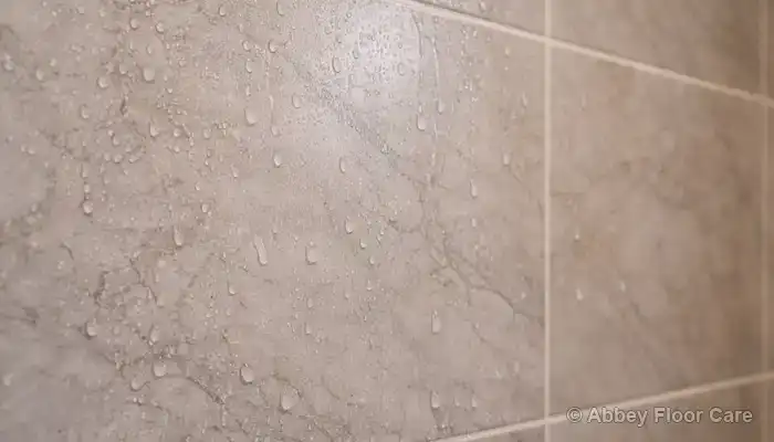 Water droplets sitting on a marble shower wall surface after use