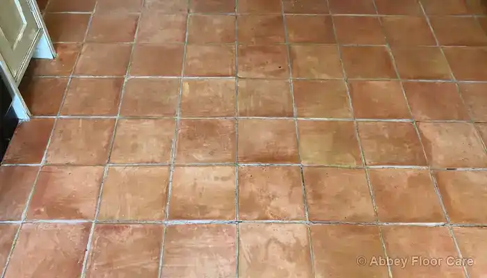Worn terracotta floor with old wax build-up and uneven colour